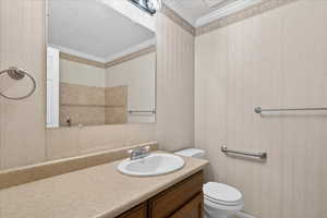 Bathroom with vanity, wallpapered walls, and crown molding