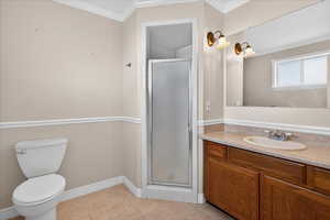Full bathroom featuring crown molding, vanity, a shower stall, and light tile patterned floors