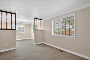 Unfurnished room with light carpet, ornamental molding, and a textured ceiling