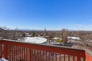 Snow covered deck with a mountain view and a balcony