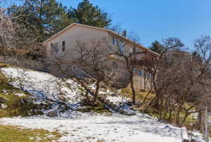 View of snow covered exterior featuring a balcony and stairs