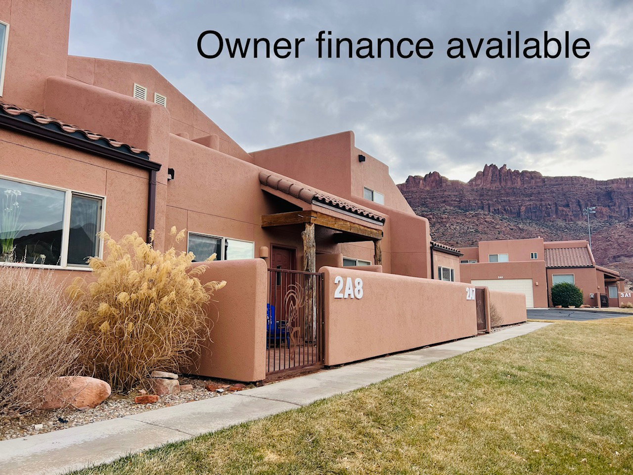 View of side of property with stucco siding, a mountain view, and a gate
