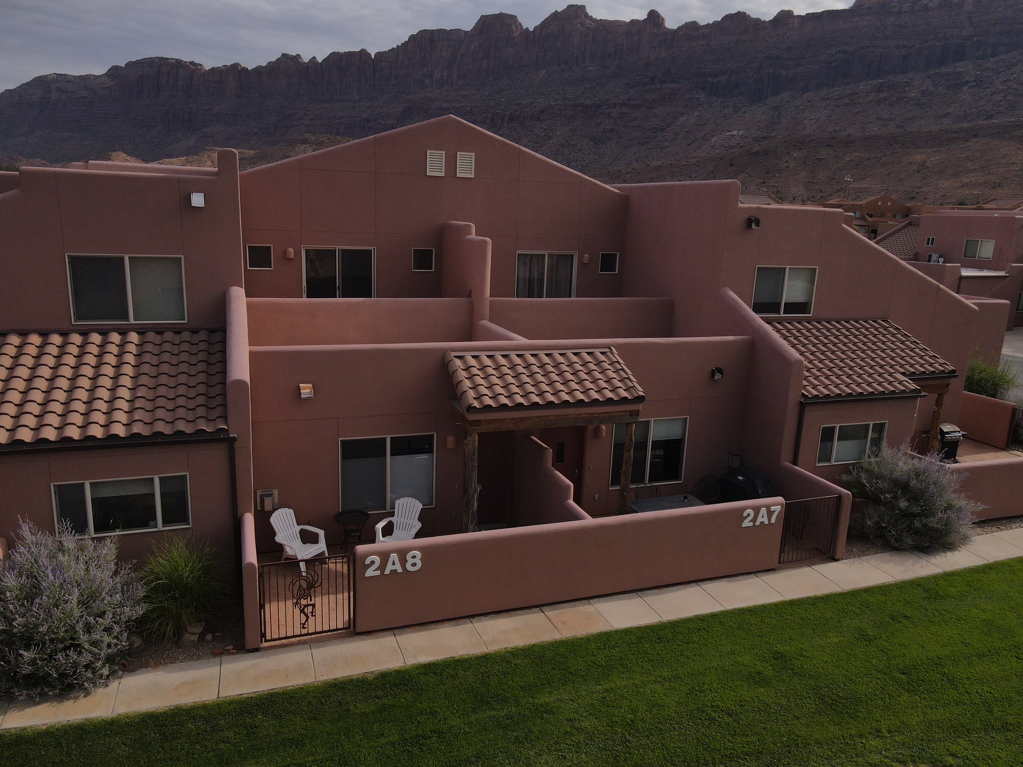Rear view of house featuring a gate, a mountain view, stucco siding, a tiled roof, and a fenced front yard