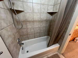 Bathroom with shower / bath combination with curtain and carpet floors