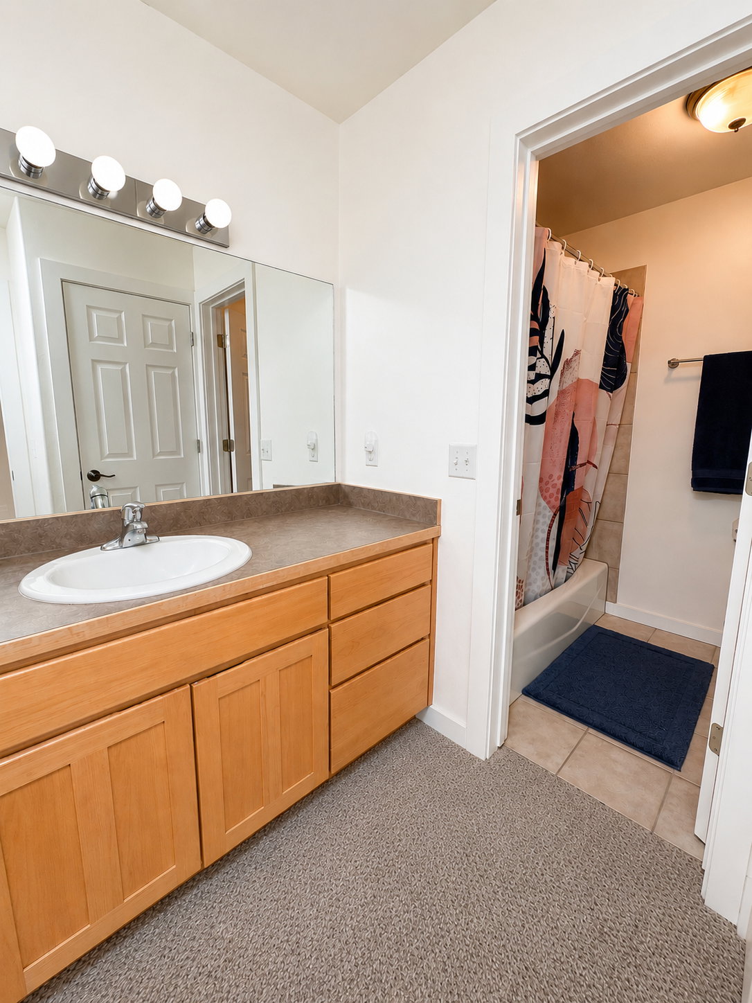Single vanity with a light wood-finish cabinet and built-in storage
