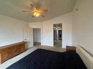Unfurnished bedroom featuring light colored carpet, ceiling fan, and vaulted ceiling