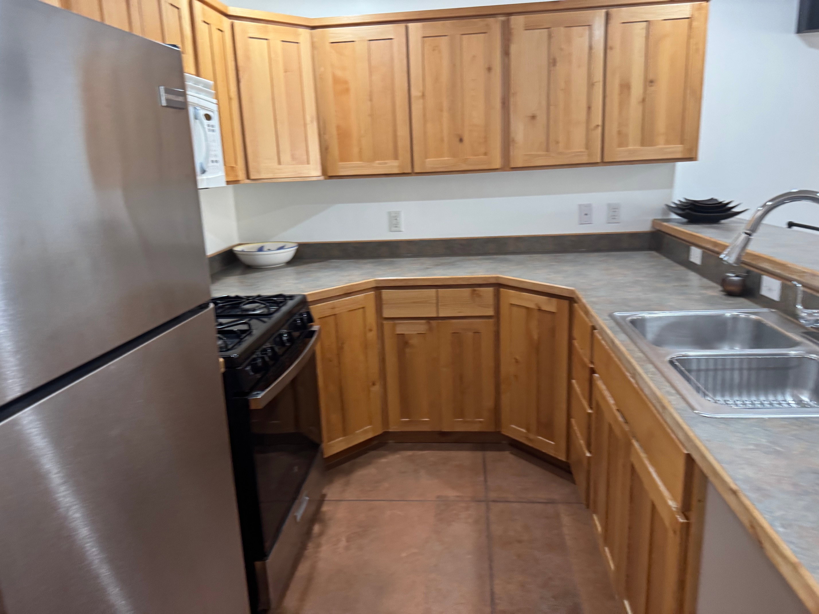 Kitchen featuring extensive wood cabinetry, stainless steel refrigerator, stainless steel oven/range, and a double basin sink