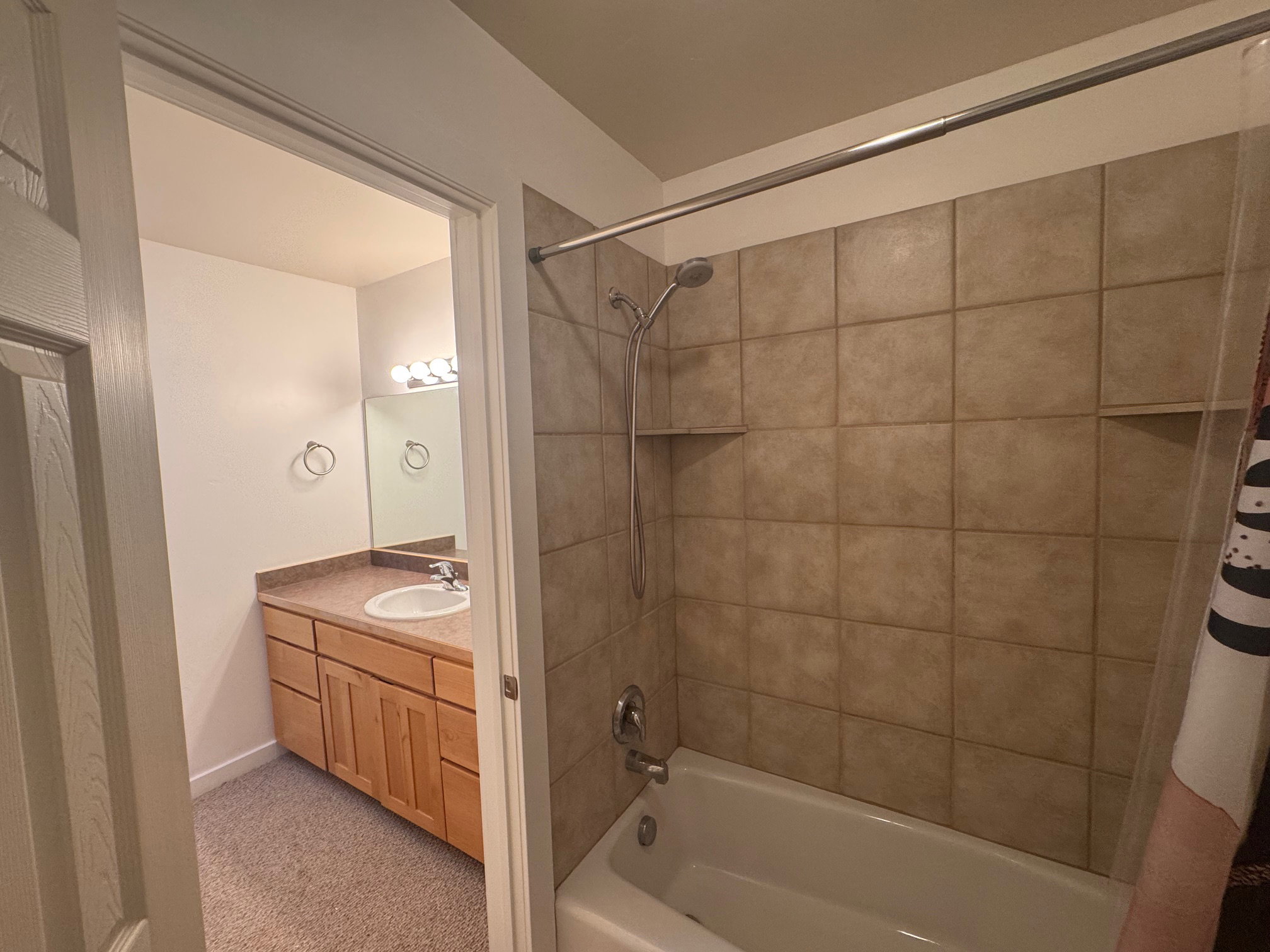 Bathroom with shower / bathtub combination with curtain, vanity, and light carpet/tile