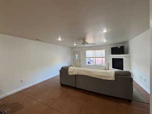 Tiled living area with a glass covered fireplace, a ceiling fan, and recessed lighting