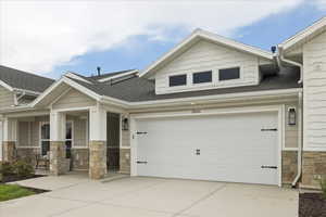 Craftsman inspired home with stone siding, roof with shingles, driveway, a porch, and an attached garage