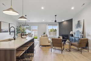 Living room featuring light wood-type flooring, a large fireplace, ceiling fan, recessed lighting, and lofted ceiling