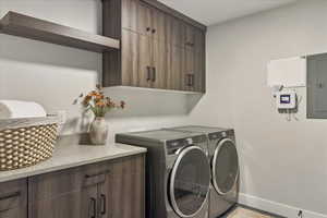 Laundry room featuring washer and clothes dryer, electric panel, and cabinet space