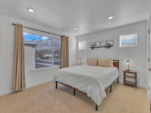 Bedroom with a mountain view, light carpet, recessed lighting, and a textured ceiling