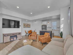 Living room with light wood-type flooring, recessed lighting, and a glass covered fireplace