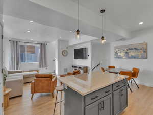 Kitchen with gray cabinets, decorative light fixtures, light wood-style flooring, and a center island