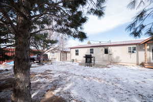 Snow covered back of property with a patio and a metal roof