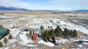 Snowy aerial view with a mountain view, view of desert landscape, a view of rural / pastoral area, and a residential view