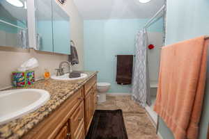 Full bath featuring double vanity and light stone finish flooring