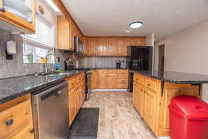 Kitchen featuring stainless steel appliances, dark stone counters, backsplash, a center island, and a breakfast bar