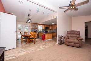 Dining area featuring vaulted ceiling, a ceiling fan, and light colored carpet