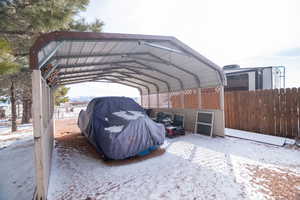 Snow covered parking area with a detached carport