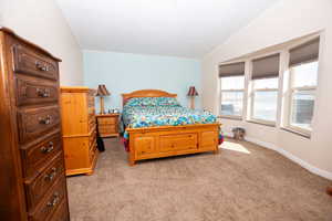 Bedroom with light carpet, crown molding, and lofted ceiling
