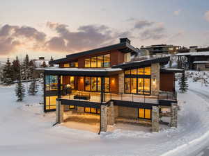 Snow covered house with a deck and stone siding