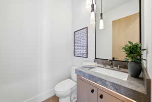 Half bathroom featuring vanity and wood finished floors