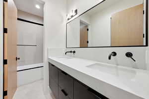 Full bath featuring combined bath / shower with glass door and double vanity