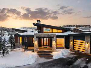 Contemporary home featuring stone siding, a chimney, and an attached garage