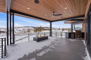 Snow covered patio with ceiling fan, a residential view, and an outdoor kitchen