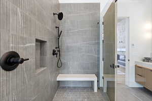 Full bathroom featuring connected bathroom, a tile shower, vanity, and light tile patterned floors