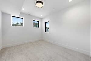Unfurnished room with light colored carpet, plenty of natural light, and recessed lighting