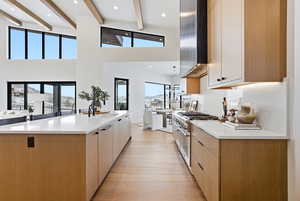 Kitchen with dual tone cabinets, recessed lighting, a large island with sink, modern cabinets, and range with two ovens