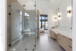 Full bath featuring ensuite bathroom, two vanities, a shower stall, and a freestanding tub