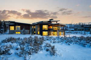 Snow covered property featuring a balcony and stone siding