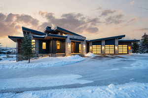 Modern home with stone siding, an attached garage, and driveway