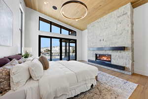 Bedroom featuring a vaulted wooden ceiling, a stone fireplace, access to outside, and wood finished floors