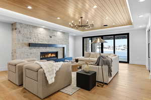 Living room with a wooden tray ceiling, light wood-style flooring, a fireplace, and suspended lighting