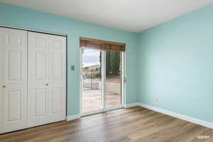 Unfurnished bedroom featuring access to outside, light wood-style floors, and a closet