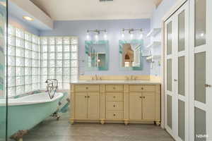 Primary Bathroom with double vanity, a soaking tub, and light tile patterned floors