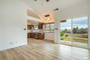 Kitchen with a chandelier, light countertops, light wood-type flooring, ceiling fan, and vaulted ceiling