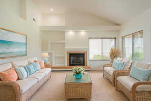 Living area with built in shelves, lofted ceiling, and a fireplace