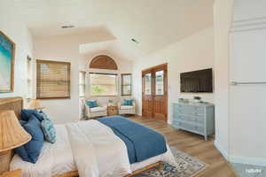 Bedroom with lofted ceiling, light wood-style flooring, and access to exterior