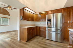 Kitchen featuring stainless steel fridge with ice dispenser, a ceiling fan, light countertops, light wood finished floors, and wood finish cabinets