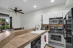 Kitchen featuring white cabinets, black appliances, open shelves, a peninsula, and ceiling fan