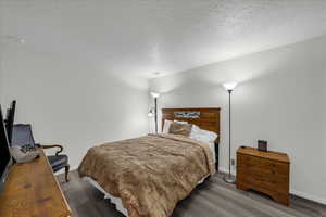 Bedroom with a textured ceiling and wood finished floors