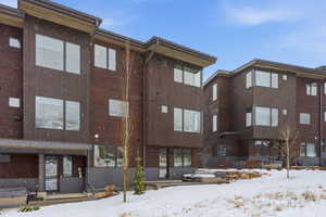 Snow covered building featuring a view of apartment building / complex