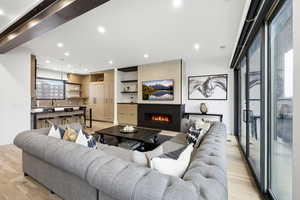 Living room featuring a large fireplace, light wood-style floors, and recessed lighting