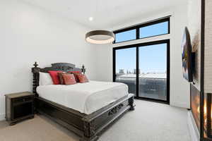 Bedroom with light carpet, access to outside, and a high ceiling